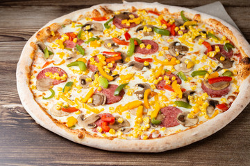 Tasty Italian pizza Mexicano on wooden background. Top view of hot pizza with chili pepper , hot sausages, onion, tomatoes and cheese. Flat lay. Advertising photo for a site or menu.