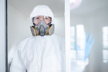 Scientist or Virologist man wearing biohazard chemical protective suit, goggles and mask. Male doctor or medical worker wearing PPE and rubber gloves for preventing Coronavirus (COVID-19) infection.