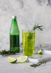 Sparkling green tea with lime in a glass, rosemary topping, tasty iced refreshment