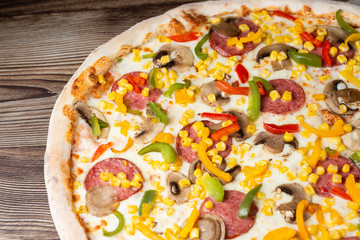 Tasty Italian pizza Mexicano on wooden background. Top view of hot pizza with chili pepper , hot sausages, onion, tomatoes and cheese. Flat lay. Advertising photo for a site or menu.