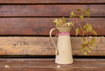 Decorative unusual flower pot in the form of a jug with a living plant on a wooden table and...