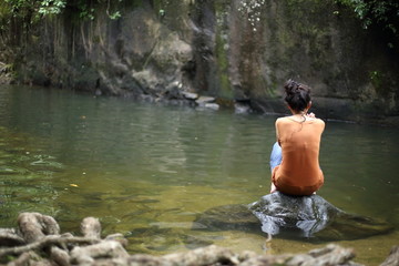Woman sitting on a rock at a waterfall