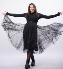 Happy beautiful girl model in black dress posing in studio isolated on white background,Teen girl in black tulle skirt , Full length portrait,opened her arms smiling
