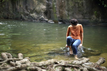 Woman sitting on a rock at a waterfall