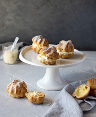Cream puffs or profiteroles filled with whipped cream dusted with sugar powder on cake stand, classic French dessert