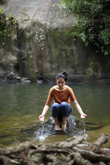 Fototapeta premium Woman sitting on a rock at a waterfall