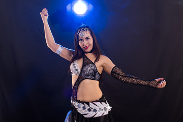 Young woman belly dancer in exotic dress with gold, dancing tribal fusion dance in studio.