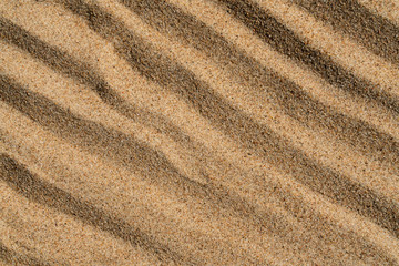 Fototapeta na wymiar background texture of yellow sand with wavy pattern