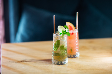 Two glass with strawberry and classic mojito cocktail with lemon and mint, cold refreshing drink or beverage with ice on bright background. Overhead view, copy space. Advertising for cafe menu
