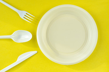 One-time white plastic utensils on a yellow background