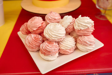 Red and white marshmallows are placed on a white square plate. Red table