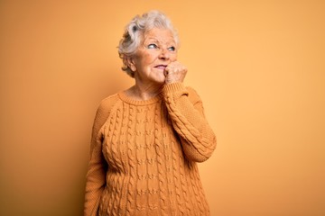 Senior beautiful grey-haired woman wearing casual sweater over isolated yellow background looking stressed and nervous with hands on mouth biting nails. Anxiety problem.