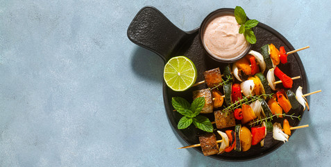 banner of ready vegan kebabs of vegetables and smoked tofu with cashew sauce and smoked paprika on...