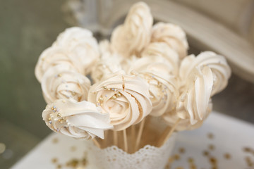 Cream colored meringues stand on sticks in a vase