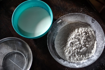 Flour, milk and sieve on a wood table