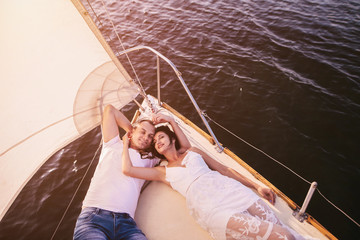 Romantic couple in love on sail boat at sunset under sunlight on yacht - Happy exclusive alternative lifestyle concept - Love story of two caucasian young people.