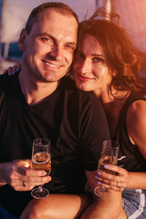Happy couple holding glass of champagne in romantic trip on yacht