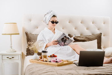 A woman in a bathrobe relaxing on the bed at home