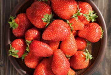 Ripe strawberries in a brown plate close-up. Top view.