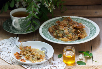 Robinia fritters served with tea and honey on a wooden table. Rustic style.
