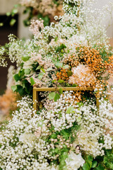 The wedding arch is decorated with small white flowers and flower arrangements of pink and white...