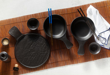 set of black empty japanese breakfast tableware on bamboo mat