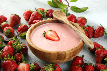 Bowl of fresh strawberry yogurt and fresh strawberries on table. Healthy food and drink concept with juicy fresh fruits and dairy dessert