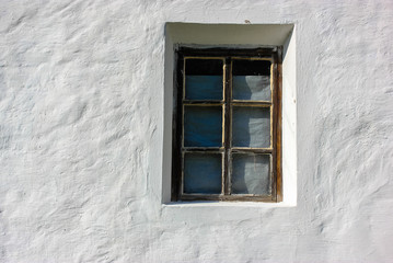 Fototapeta premium An old window against the background of a white clay house in the village in summer.