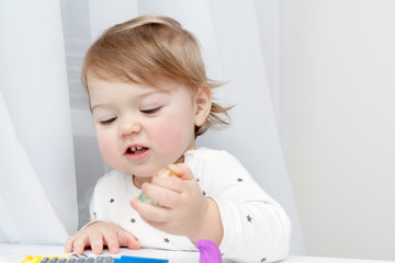 A small child plays at the table, does not look at the camera. Child development