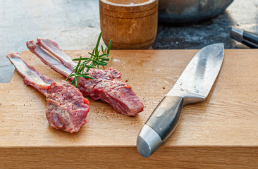 Lamb chops with rosemary and spices and big knife on wooden cutting board