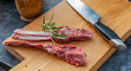 Lamb chops with rosemary and spices and big knife on wooden cutting board