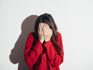 Frightened young girl on a background of a white wall. Domestic violence.