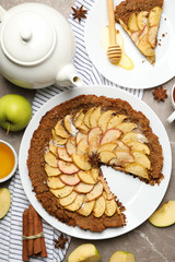 Composition with apple pie and ingredients on gray background, top view