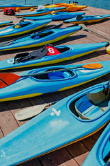 colored kayaks, ball, helmet and paddle on a wooden pier