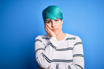 Young beautiful woman with blue fashion hair wearing casual sweater standing at studio thinking looking tired and bored with depression problems with crossed arms.
