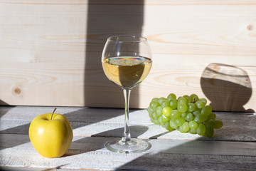 Glass of white wine and grape on wooden background