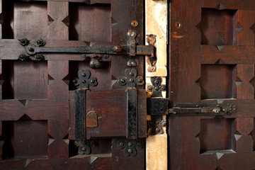 A close-up of a rustic lock and hinges on a church door in the UK