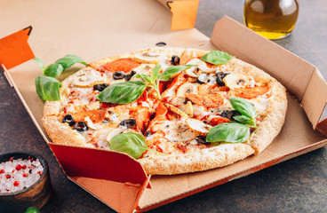 Pizza in a orange cardboard box on a dark background. Pizza delivery. Stay at home concept.