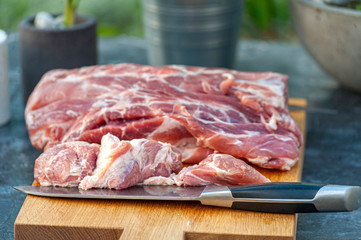 Big piece of beef or pork meat and a big knife on cutting board, outdoors