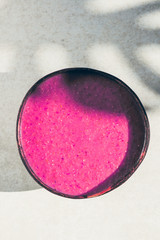 Pink Smoothie from Banana, Strawberries and Pint Matcha in the Coconut Shell Bowl, strong shadows. Healthy summer breakfast