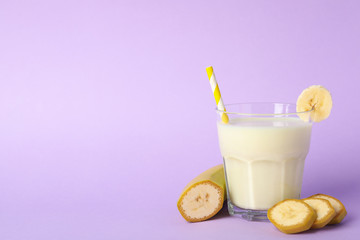 Glass of banana milkshake on violet background. Summer drink