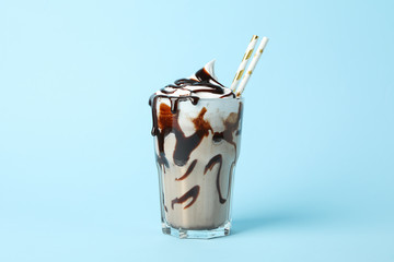 Glass of chocolate milkshake on blue background. Summer drink