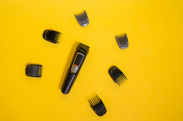 Electric hair clipper with various attachments on a yellow background