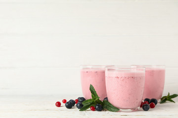 Delicious berry milkshakes on wooden table. Summer drink