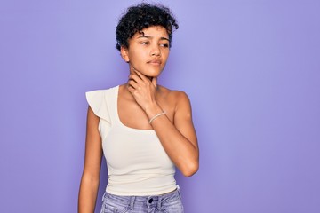 Young beautiful african american afro woman wearing casual t-shirt over purple background Touching painful neck, sore throat for flu, clod and infection