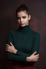 a girl in a green sweater and skirt on a dark background