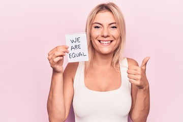 Young beautiful blonde woman asking for equality holding paper with we are equal message smiling...