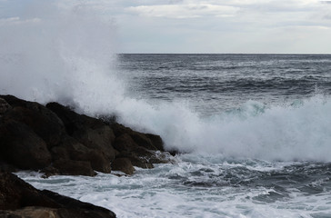 Storm clouds are approaching and with them a strong wind, which has brought a huge number of medium waves, which persistently crash the rocky cliffs. Dominance of the seas and ocean. Dangerous situati