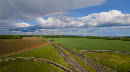 Full rainbow over the highway in green fields