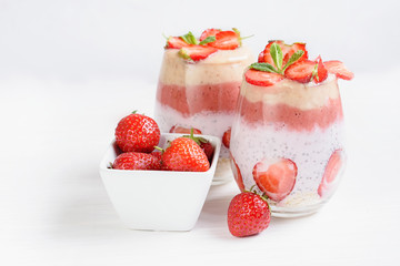 Glass of sweet delicious homemade layered smoothie dessert made from fruits and berries. delicious Strawberry banana milkshake, vegan raw food. Selective focus. Chia pudding